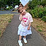child, girl, sidewalk, street, tree, grass, house, cloud, sky, pink_tshirt, white_skirt, white_shoes, socks, pose, cute, outdoor, daylight, hair_tie, expression, residential_area