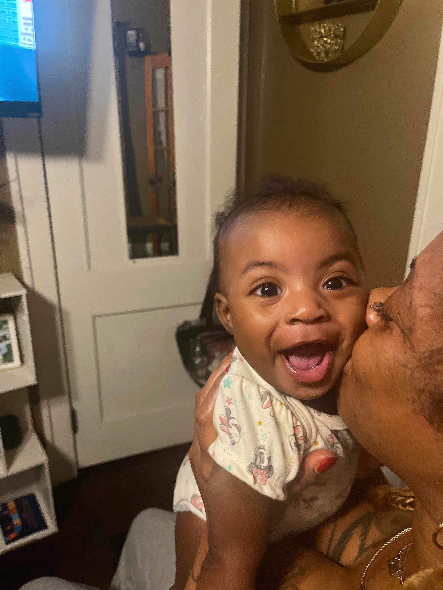 Kalilah is registered to the contest to win money with this photo: baby, infant, child, smile, laugh, kiss, adult, person, face, eyes, onesie, hand, affection, joy, home_interior, door, mirror, shelf, television, furniture