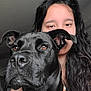 dog, black_dog, person, portrait, close_up, brown_eyes, long_hair, indoor, face, canine, pet, animal, companion, looking_away, calm, young_adult, black_hair, cute, indoors, friendship
