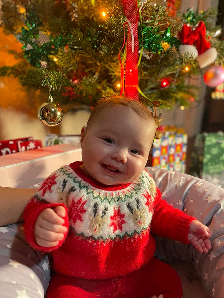 Mia participe au concours pour gagner de l'argent avec cette photo : baby, baby_toddler_clothing, beauty, child, christmas_decoration, christmas_eve, christmas_ornament, christmas_tree, event, eye, happy, holiday, holiday_ornament, joy, ornament, person, plant, red, sleeve, smile