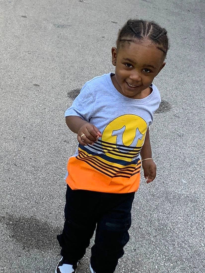 Jamal is registered to the contest to win money with this photo: asphalt, child, cool, hairstyle, happy, joy, orange, people, person, play, smile, standing, t_shirt, toddler, vacation, yellow