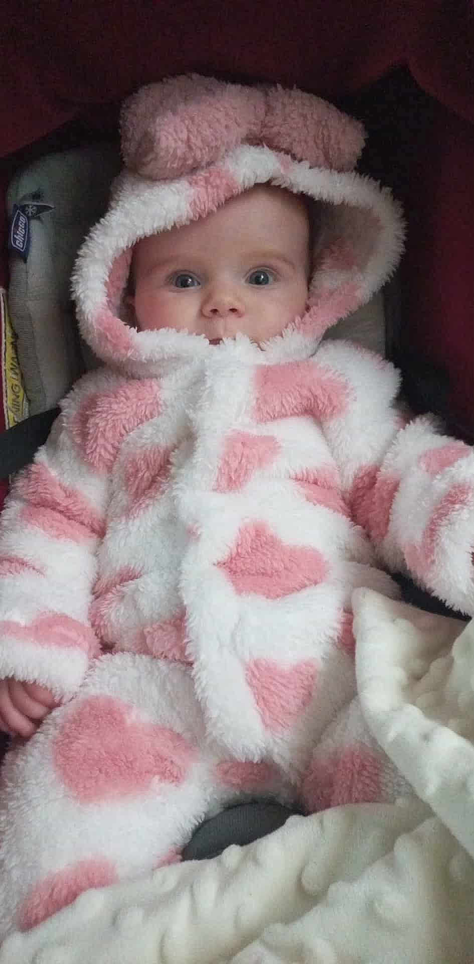 Léna participe au concours pour gagner de l'argent avec cette photo : baby, child, infant, hood, pink, white, fluffy, coat, warm, cute, face, eyes, hands, blanket, car_seat, soft, clothing, portrait, indoor, adorable