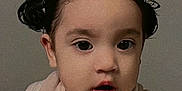 Zylah joined the competition — help win amazing prizes! toddler, child, portrait, face, expression, hair_buns, black_hair, indoors, neutral_background, clothing, curious, young_child, cute, baby, skin, mouth_open, eyes, person, head, closeup