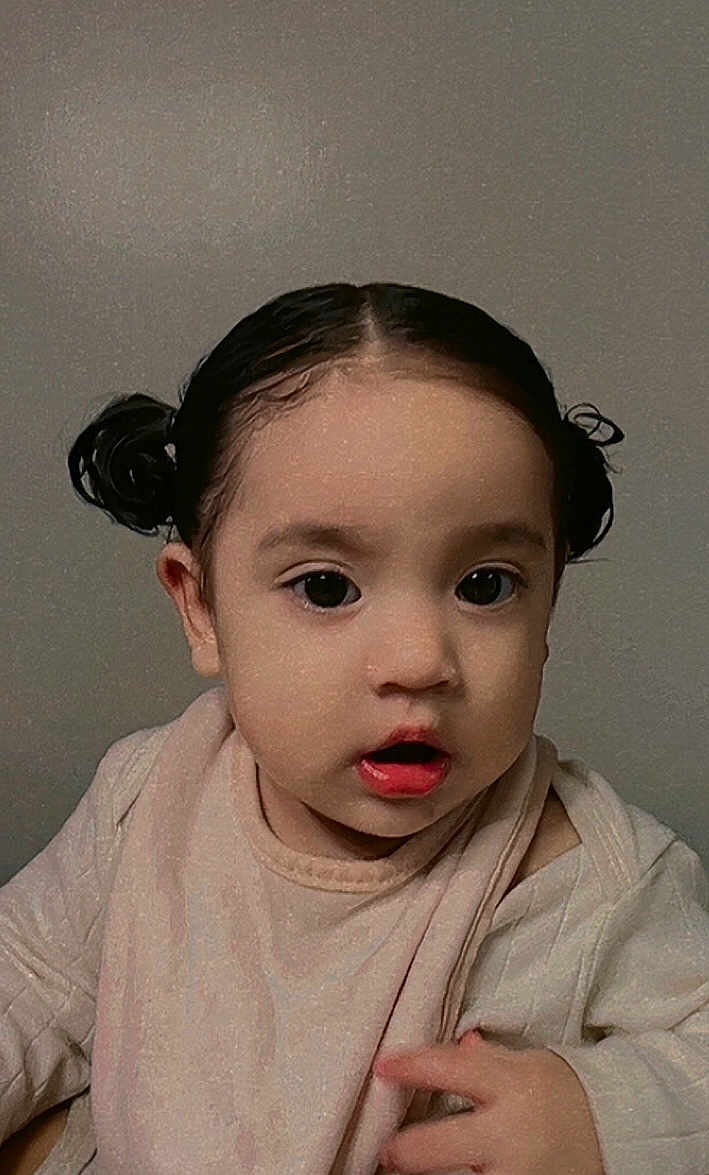 Zylah joined the competition — help win amazing prizes! toddler, child, portrait, face, expression, hair_buns, black_hair, indoors, neutral_background, clothing, curious, young_child, cute, baby, skin, mouth_open, eyes, person, head, closeup