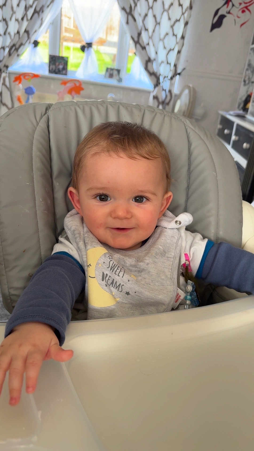 Kaiden-Bryan joined the competition — help win amazing prizes! baby, bib, child, clothing, curtains, cute, expression, face, furniture, hand, happy, high_chair, home, indoor, infant, person, reaching, smiling, window, young