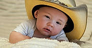 Andrew joined the competition — help win amazing prizes! baby, cowboy_hat, blanket, infant, cute, portrait, child, face, hat, lying_down, soft_texture, white_clothing, indoors, relaxed, closeup, adorable, young_child, headwear, skin, expression
