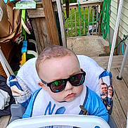 Andrew joined the competition — help win amazing prizes! baby, child, sunglasses, swing, porch, wood, hair, blue_clothing, bib, outdoor, greenery, cardboard_boxes, fence, reflection, seat, rope, casual, expression, face, sunny