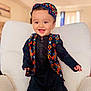 Alyan is registered to the contest to win money with this photo: toddler, child, smiling, traditional_clothing, colorful, vest, hat, black_outfit, indoor, armchair, white_furniture, happy, cute, portrait, baby, person, standing, home, bright, innocence