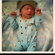 Carson is registered to the contest to win money with this photo: baby, newborn, sleeping, onesie, hat, blanket, soft, cozy, infant, portrait, cute, peaceful, child, sleep, pattern, clothing, resting, indoors, warm, polaroid