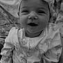 baby, infant, smile, headband, bow, pajamas, dinosaur_pattern, blanket, cozy, portrait, happy, child, cute, monochrome, black_and_white, face, clothing, sitting, indoors, young