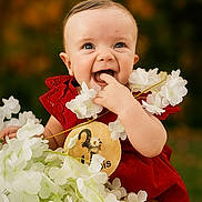 Aurore participe au concours pour gagner de l'argent avec cette photo : baby, child, smiling, red_dress, white_flowers, portrait, cute, happy, outdoor, nature, infant, flower_garland, close_up, young, skin, face, eyes, hand, laughing, background_blur