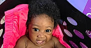 Josiah joined the competition — help win amazing prizes! baby, child, basket, pink_jacket, curly_hair, indoor, diaper, playful, expression, black_basket, floor, packaging, colorful, cute, sitting, person, small_child, skin, hand, face