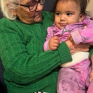 Kalaya is registered to the contest to win money with this photo: elderly_woman, baby, glasses, green_sweater, pink_outfit, indoor, seated, leopard_print, holding, affection, family, person, portrait, caring, happy, child, senior, cute, warmth, love
