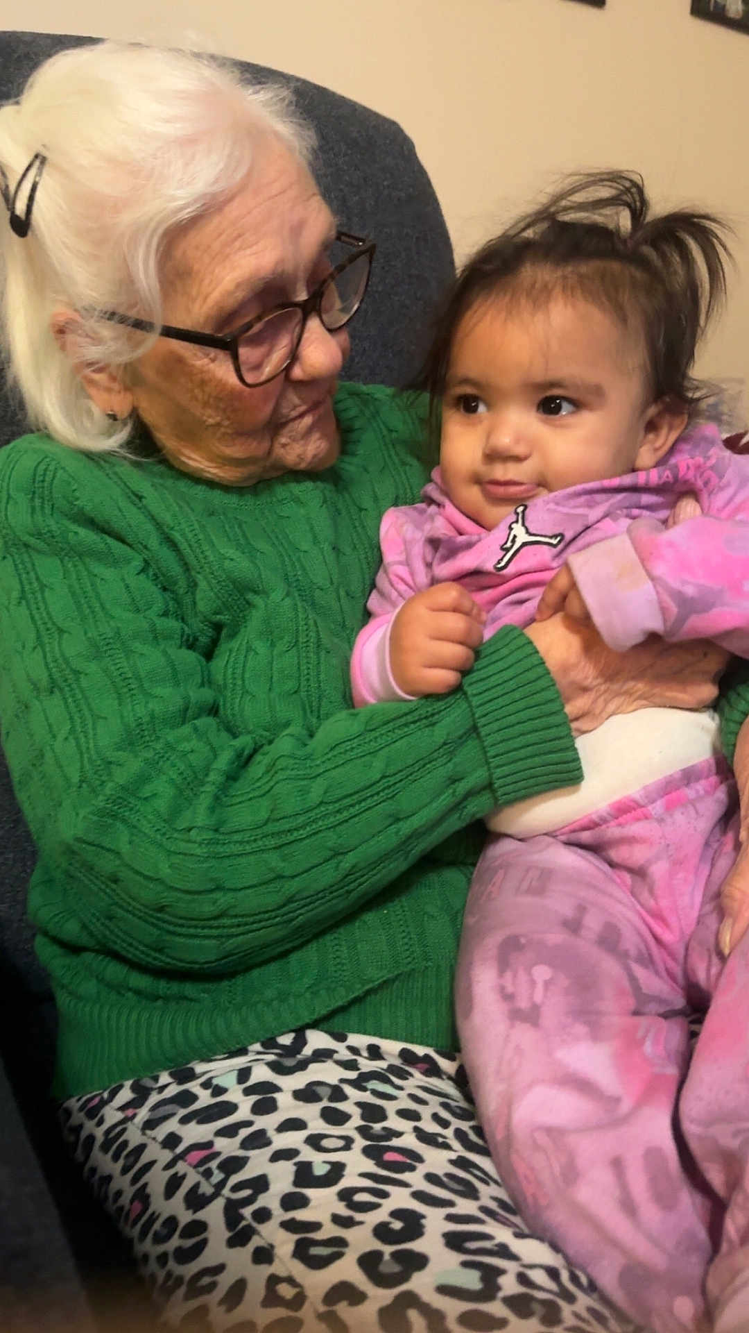 Kalaya is registered to the contest to win money with this photo: elderly_woman, baby, glasses, green_sweater, pink_outfit, indoor, seated, leopard_print, holding, affection, family, person, portrait, caring, happy, child, senior, cute, warmth, love