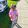 Malani is registered to the contest to win money with this photo: child, girl, sidewalk, grass, car, pink_jacket, plaid_dress, shoes, snack, sunlight, shadow, outdoor, daylight, urban, parked_car, happy, hair_beads, smile, person, casual_clothing