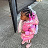 child, girl, pink_jacket, beads, hair_braids, sidewalk, chain_link_fence, outdoor, curious, winter_clothing, boots, backpack, urban, concrete, street, portrait, standing, fashion, accessories, daylight