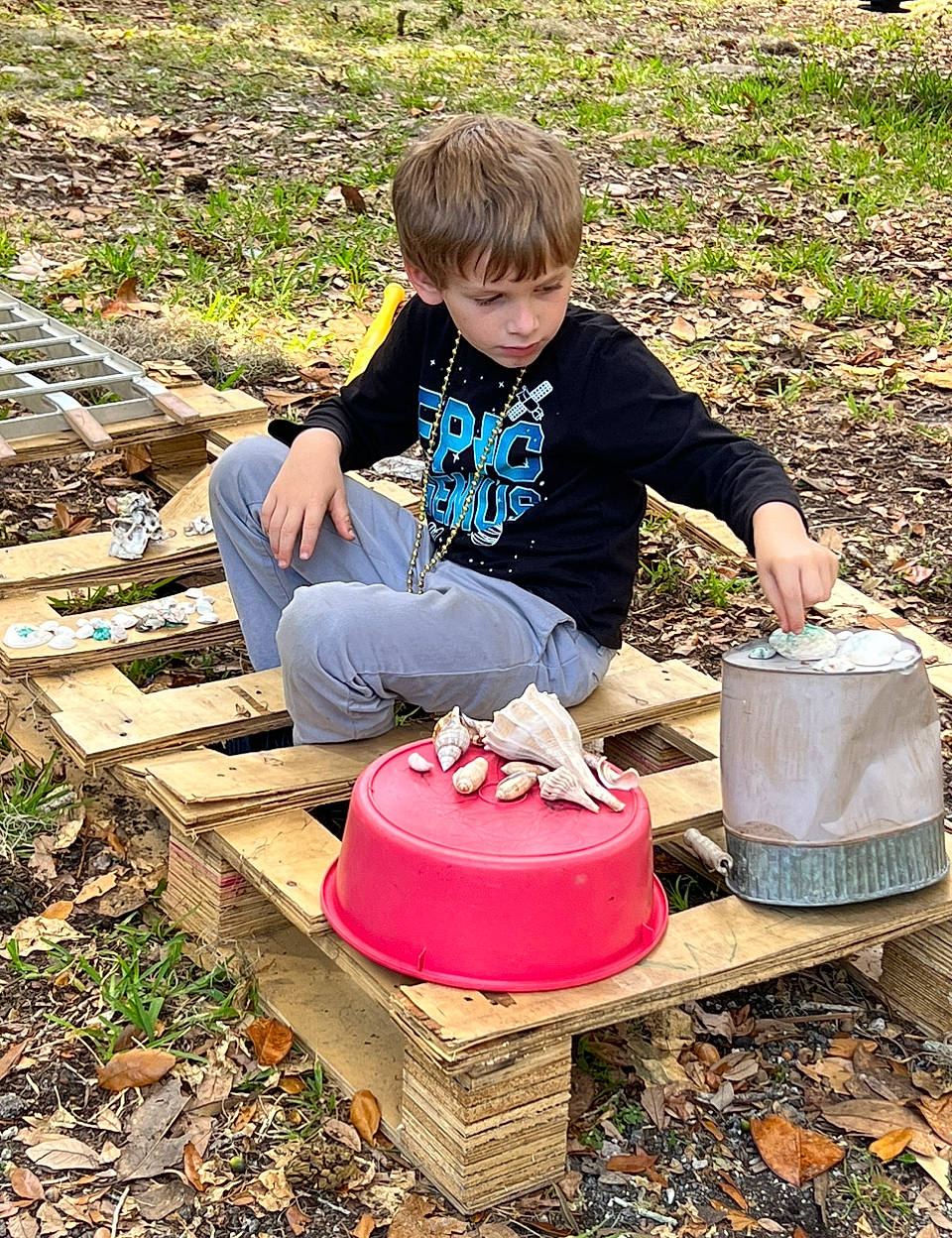 Kenneth is registered to the contest to win money with this photo: automotive_wheel_system, child, cooking, cookware_and_bakeware, fun, garden, gardening, grass, leisure, people_in_nature, person, picnic, play, pottery, recreation, sharing, shorts, sitting, soil, t_shirt