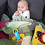 Enoah participe au concours pour gagner de l'argent avec cette photo : baby, infant, child, face, hand, fingers, blanket, couch, pillow, toy, book, onesie, knit_blanket, colorful, indoor, portrait, sitting, head, nursery_toy, fabric