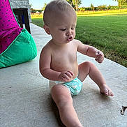 Titan is registered to the contest to win money with this photo: baby, child, diaper, outdoor, porch, concrete, grass, bean_bag, watermelon_pattern, curious, puckered_lips, sunlight, greenery, tree, summer, cute, sitting, infant, skin, expression