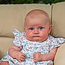 baby, child, blue_eyes, floral_dress, cushion, beige, chair, cute, portrait, infant, serious_expression, skin, human, sitting, indoors, plump, hands, face, head, person