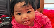Amira is registered to the contest to win money with this photo: baby, child, pink_clothing, tongue_out, crawling, red_carpet, indoor, face, cute, expression, person, hair, toy_wheel, floor, hand, head, playtime, home, infant, smiling