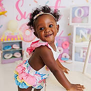 Willow is registered to the contest to win money with this photo: toddler, child, smiling, headband, curly_hair, colorful_clothing, chair, donut_theme, party, balloons, pastel_colors, indoor, happy, cute, celebration, decorations, baby, playful, portrait, person
