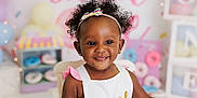 Willow is registered to the contest to win money with this photo: child, toddler, smile, happy, headband, curly_hair, earrings, white_outfit, pink, decorations, donuts, party, birthday, chair, indoor, portrait, cute, celebration, colorful, background