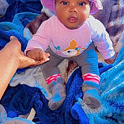 Alohianiey joined the competition — help win amazing prizes! baby, child, hat, hand, blanket, clothing, sitting, indoor, person, footwear, sock, colorful, curious, support, young_child, portrait, cute, holding_hand, soft_texture, warm