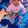 baby, child, hat, hand, blanket, clothing, sitting, indoor, person, footwear, sock, colorful, curious, support, young_child, portrait, cute, holding_hand, soft_texture, warm