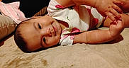 Reyna is registered to the contest to win money with this photo: baby, infant, child, portrait, lying_down, blanket, bed, floral_clothing, strawberry_pattern, baby_hand, adult_hand, toes, feet, face, eyes, smiling, indoors, cozy, candid, 家庭