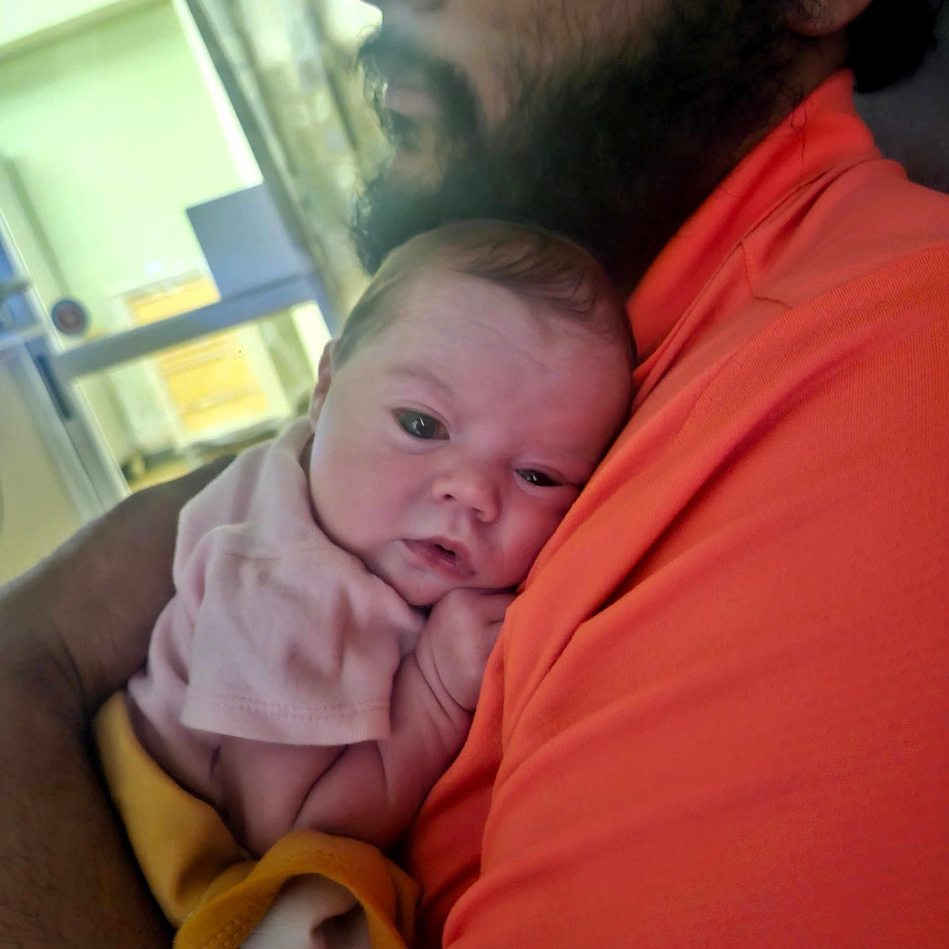 Jadence is registered to the contest to win money with this photo: baby, infant, adult, shoulder, hug, closeup, indoor, person, face, curly_hair, orange_shirt, soft_clothing, skin, head, hand, comfort, resting, human, portrait, warm_colors