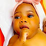 baby, infant, child, headband, pink_bow, hand, thumb_sucking, skin, face, eyes, earring, lying_down, cute, adorable, closeup, expression, portrait, indoor, soft_light, toddler
