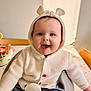 baby, child, smiling, hoodie, knitted, white, blue_eyes, cute, happy, indoor, table, chair, toy, buttoned_clothing, portrait, seated, infant, face, warm_clothing, playful