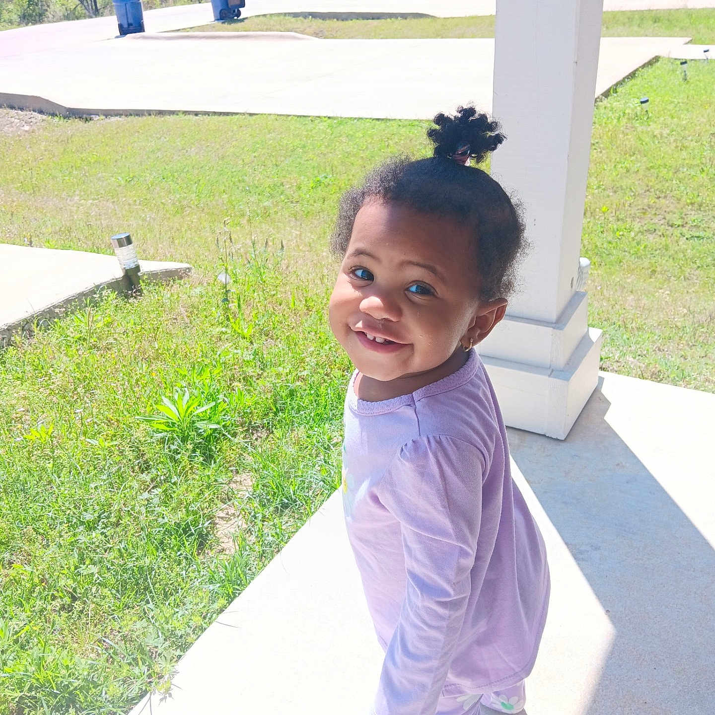Nykeriah joined the competition — help win amazing prizes! casual_wear, child, concrete, cute, daylight, earrings, grass, greenery, hair_bun, happy, outdoor, pajamas, person, playful, porch, purple_clothing, small_child, smiling, sunlight, toddler