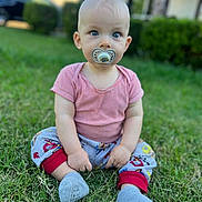 Kevin is registered to the contest to win money with this photo: baby, child, grass, outdoor, pacifier, sitting, pajamas, shirt, blue_eyes, cute, infant, nature, greenery, daylight, young_child, person, sock, casual_clothing, background_blur, portrait