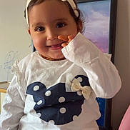 Marya is registered to the contest to win money with this photo: bow, casual, child, clothing, cute, face, furniture, happy, headband, home, indoor, person, playful, polka_dot, portrait, sitting, smiling, toddler, white_shirt, young_child