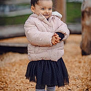Giulia participe au concours pour gagner de l'argent avec cette photo : child, puffy_jacket, black_skirt, striped_socks, white_shoes, wood_chips, playground, outdoor, smile, standing, pony_tail, cute, winter_clothing, fashion, happy, person, young_child, casual, nature, park