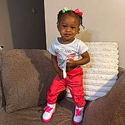 Gianniah joined the competition — help win amazing prizes! child, toddler, girl, portrait, smiling, standing, indoor, couch, furniture, bows, braids, hair_accessories, t_shirt, red_pants, sneakers, colorful_clothing, living_room, cushions, fashion, photography
