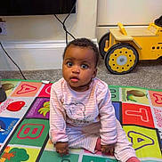 Miracle joined the competition — help win amazing prizes! baby, child, pajamas, play_mat, toy_vehicle, floor, indoor, colorful, alphabet, curious, sitting, carpet, person, infant, cute, young_child, pink_clothing, room, playtime, expression