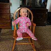 Braelynn joined the competition — help win amazing prizes! baby, child, onesie, pink_clothing, rocking_chair, wooden_chair, smiling, indoor, carpet, furniture, cabinet, dresser, face, person, happy, cute, home, room, seated, infant
