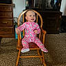 baby, child, onesie, pink_clothing, rocking_chair, wooden_chair, smiling, indoor, carpet, furniture, cabinet, dresser, face, person, happy, cute, home, room, seated, infant