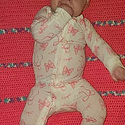Aryah is registered to the contest to win money with this photo: baby, blanket, butterfly_pattern, child, crochet, cute, fabric, hand_in_mouth, headband, indoor, infant, lying_down, one_arm_outstretched, patterned_clothing, person, pink, portrait, sleeper, soft_lighting, wide_eyes