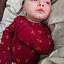 baby, infant, child, face, blue_eyes, clothing, onesie, red, floral_pattern, blanket, fabric, soft, lying_down, skin, expression, portrait, cute, indoors, young, resting