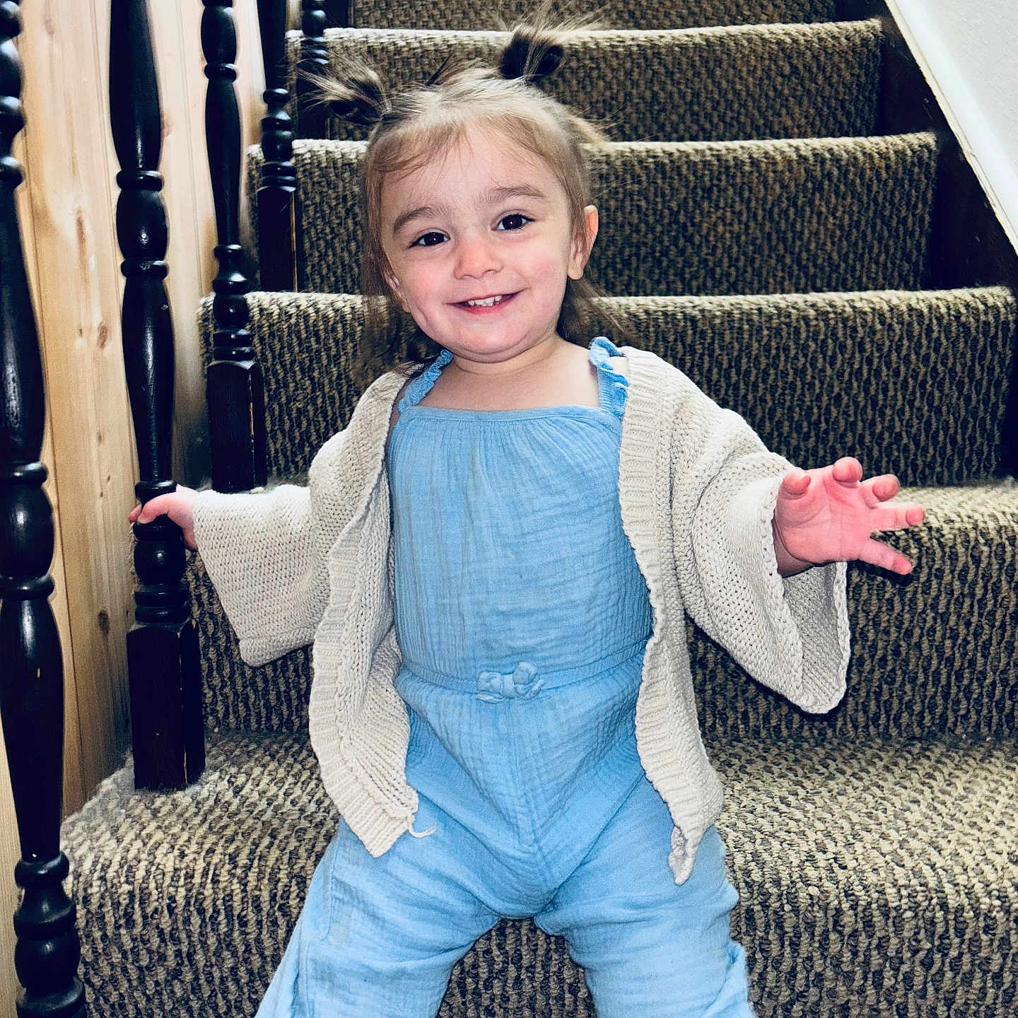 Brixley is registered to the contest to win money with this photo: baby, blue_outfit, cardigan, carpet, child, clothing, cute, fun, happy, home, indoors, person, pigtails, playful, portrait, smiling, stairs, toddler, wooden_banister, young_child