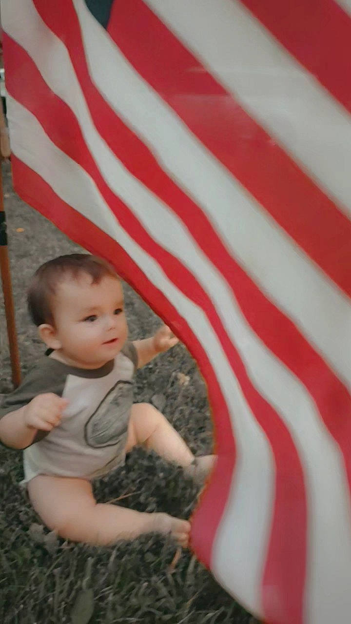 Johnathan is registered to the contest to win money with this photo: baby, baby_toddler_clothing, child, event, flag, flag_day_usa, flag_of_the_united_states, fun, gesture, grass, happy, holiday, leisure, pattern, people_in_nature, person, play, recreation, sitting, toddler