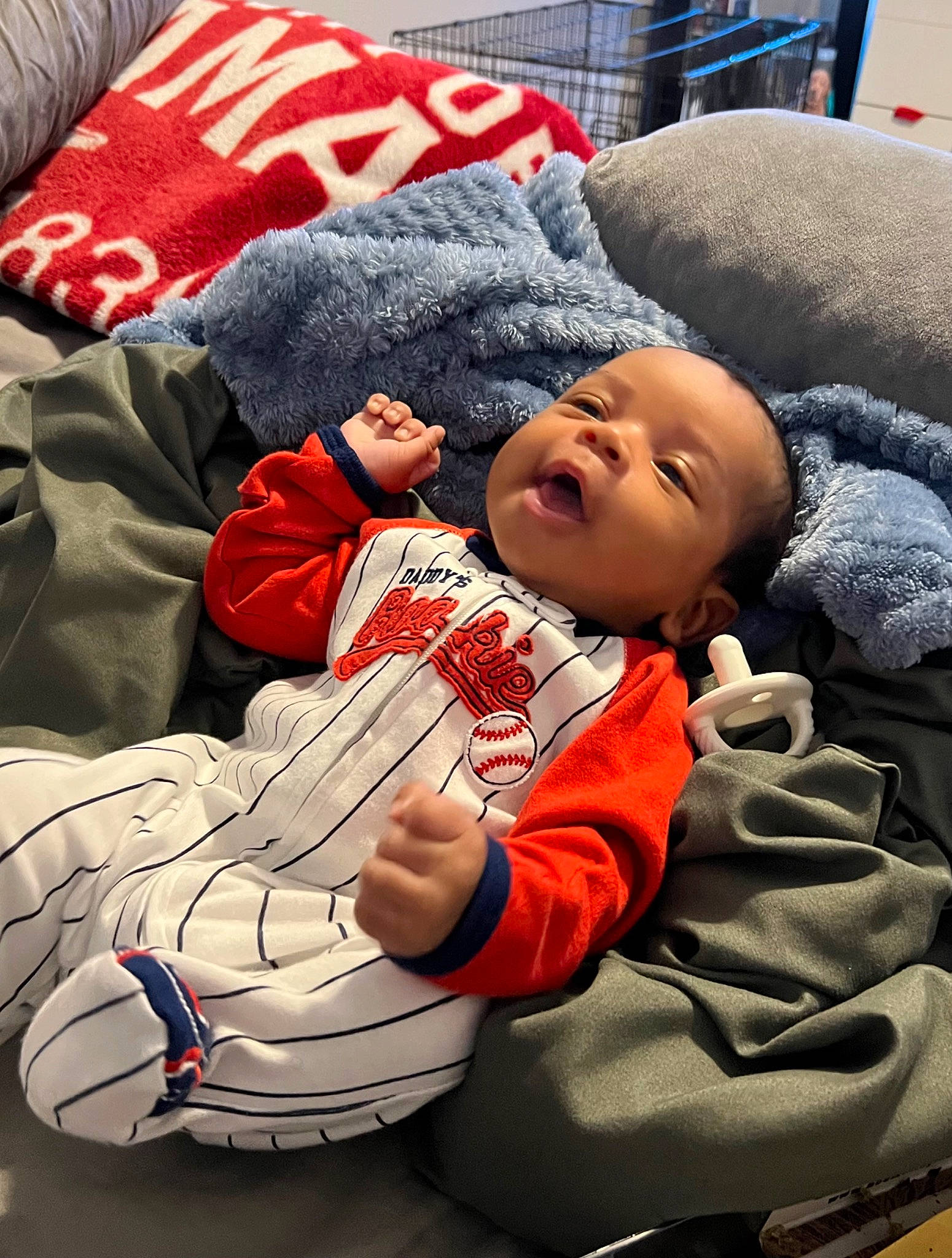 Saint is registered to the contest to win money with this photo: baby, baby_toddler_clothing, ball, carmine, child, comfort, event, face, fun, fur, gesture, happy, head, lap, nap, person, sitting, smile, sports_gear, sportswear