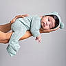 newborn, baby, infant, child, portrait, lying_down, held, adult_arms, mint_green, outfit, knit_hat, onesie, sleepy, calm, face, hands, studio, gray_background, closeup, photography