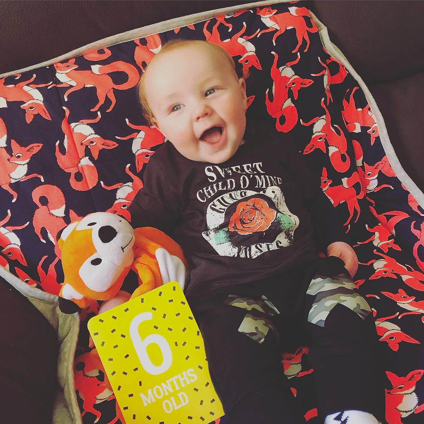 Duncan is registered to the contest to win money with this photo: baby, baby_products, baby_toddler_clothing, baby_toys, bib, car_seat, cheek, child, linens, orange, outerwear, pattern, person, play, product, sleeve, t_shirt, textile, toddler