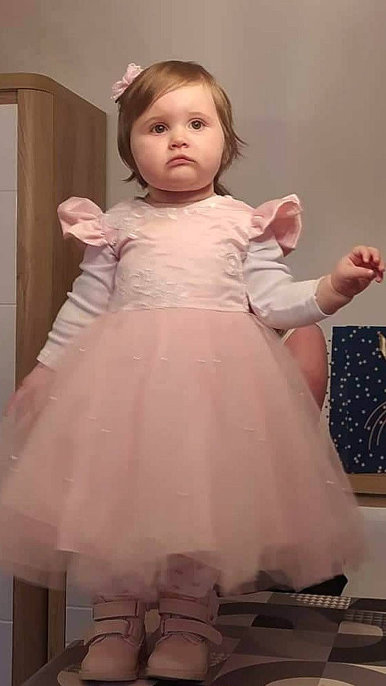 Elyna participe au concours pour gagner de l'argent avec cette photo : baby_toddler_clothing, bridal_party_dress, cheek, dress, eye, face, flash_photography, gesture, hair, head, human_body, joint, neck, one_piece_garment, person, pink, shoulder, skin, sleeve, standing