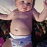 arms_outstretched, baby, child, chubby_cheeks, closeup, curious, cute, diaper, eyes, face, flesh, head, indoor, infant, lying_down, mouth, patterned_blanket, person, skin, torso
